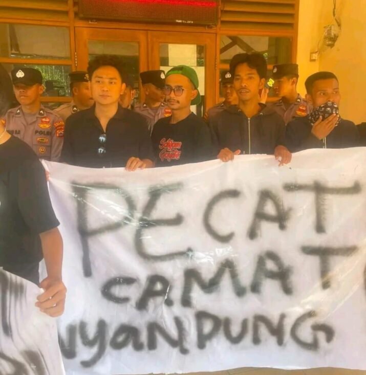 Massa aksi warga Saketi membawa spanduk bertuliskan tuntutan pencopotan camat dalam unjuk rasa di depan Kantor Kecamatan Saketi, Jumat 25 September 2025.